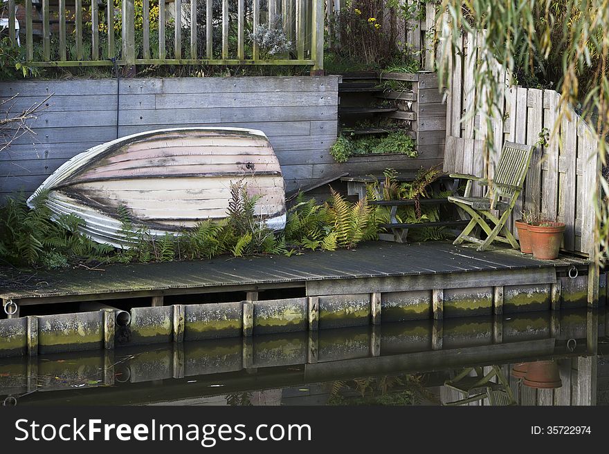 Boat resting on its side in the garden near the water. Boat resting on its side in the garden near the water
