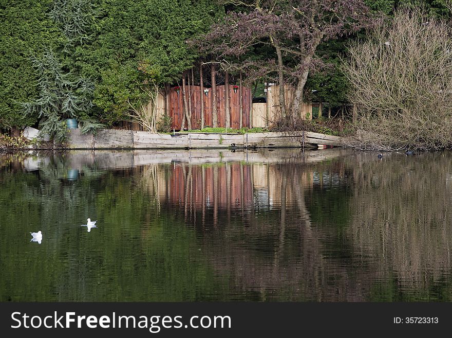 Wooden fence and reflections in the water of a lake. Wooden fence and reflections in the water of a lake