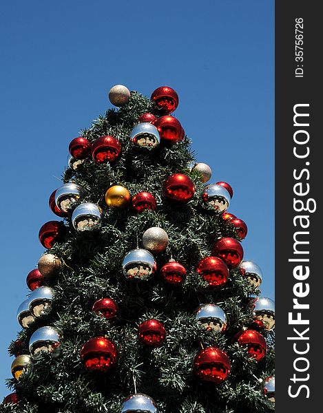 A Christmas tree decorated with red and silver and gold baubles glints under an African sun and blue summer sky. A Christmas tree decorated with red and silver and gold baubles glints under an African sun and blue summer sky.