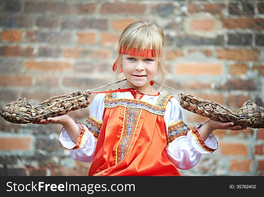 Little girl in national costumes with bast