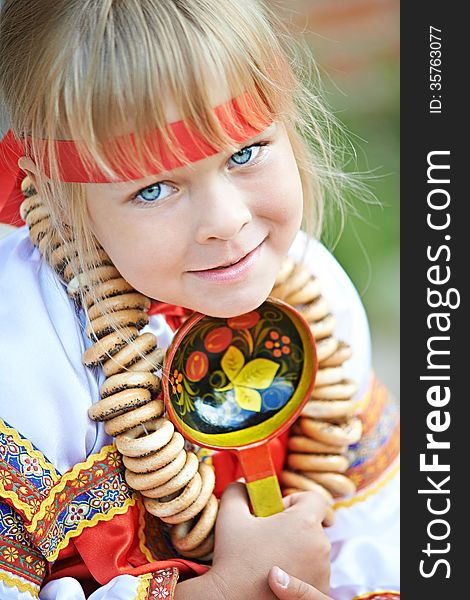 Russian girl in national costume with a spoon and bagels. Russian girl in national costume with a spoon and bagels