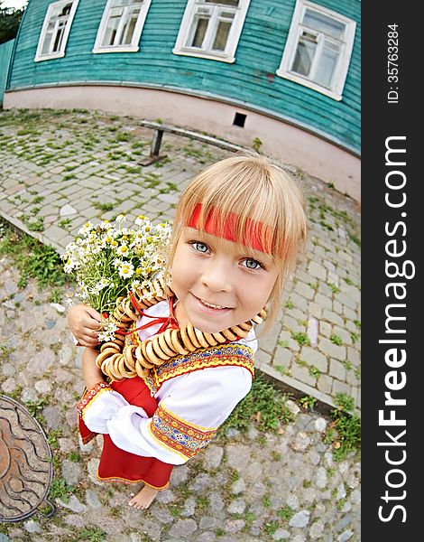 Russian girl in national costume with bagels and flowers on village