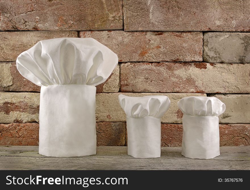 Three white toques on brick wall background. Three white toques on brick wall background