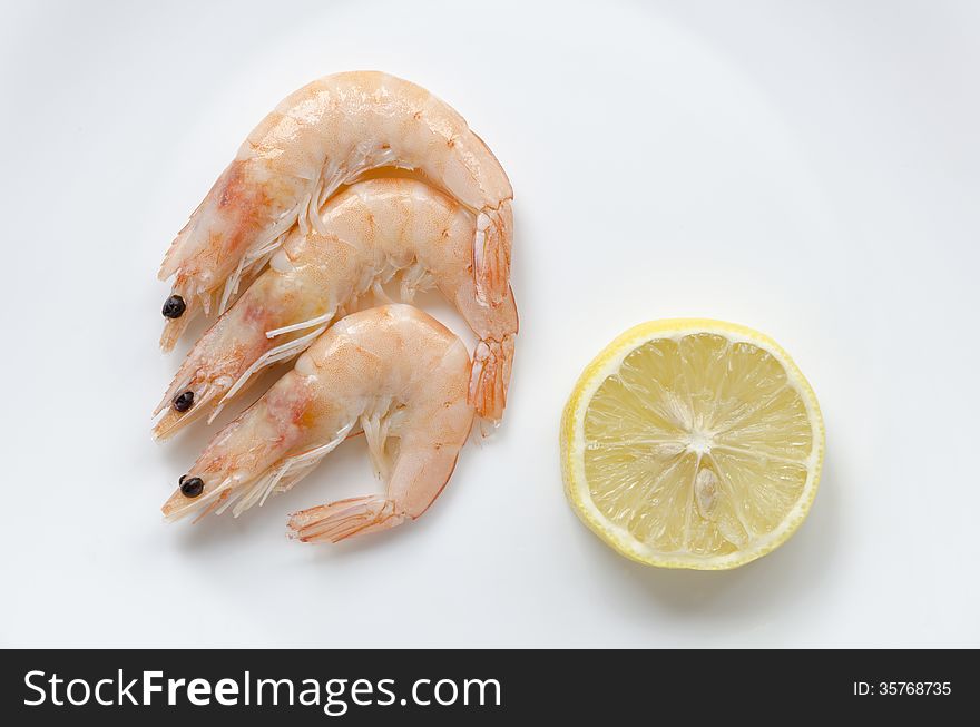 Three shrimps with lemon slice on white plate
