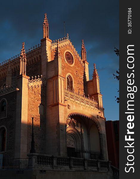 Old church in Madrid at sunset under gloomy clouds with sunbeam