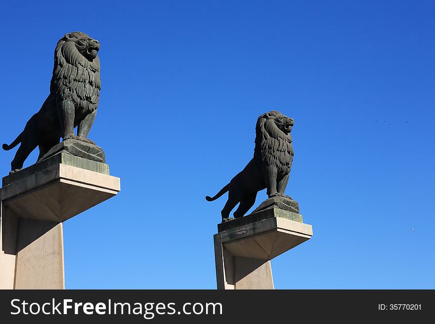 Pair of black metal lions sculpture against blue sky, Zaragoza, Spain
