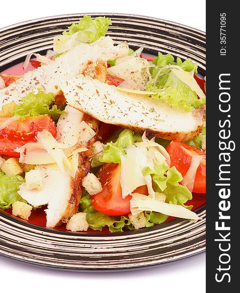 Traditional Caesar Salad with Grilled Chicken Breast, Garlic Crouton, Lettuce, Tomatoes and Grated Parmesan Cheese on Striped Plate closeup on white background