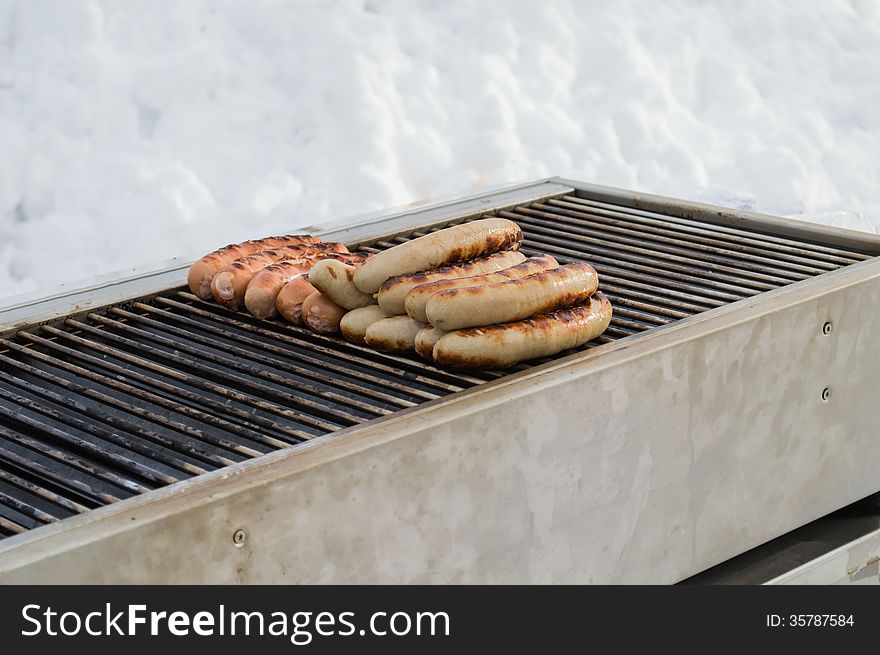 Grilled traditional German sausage hot dog on a grill during a winter day. Grilled traditional German sausage hot dog on a grill during a winter day