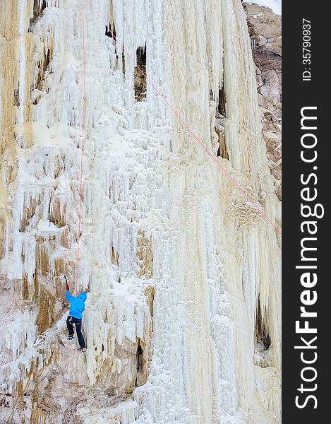 Young man climbing the ice using ice axe