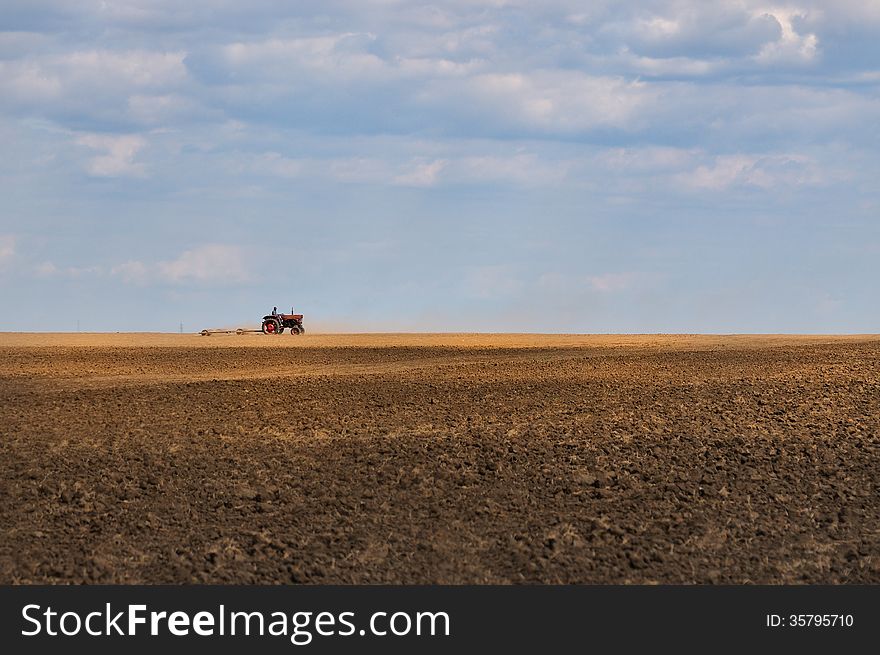 Tractor working in the field betwen between sky and ground