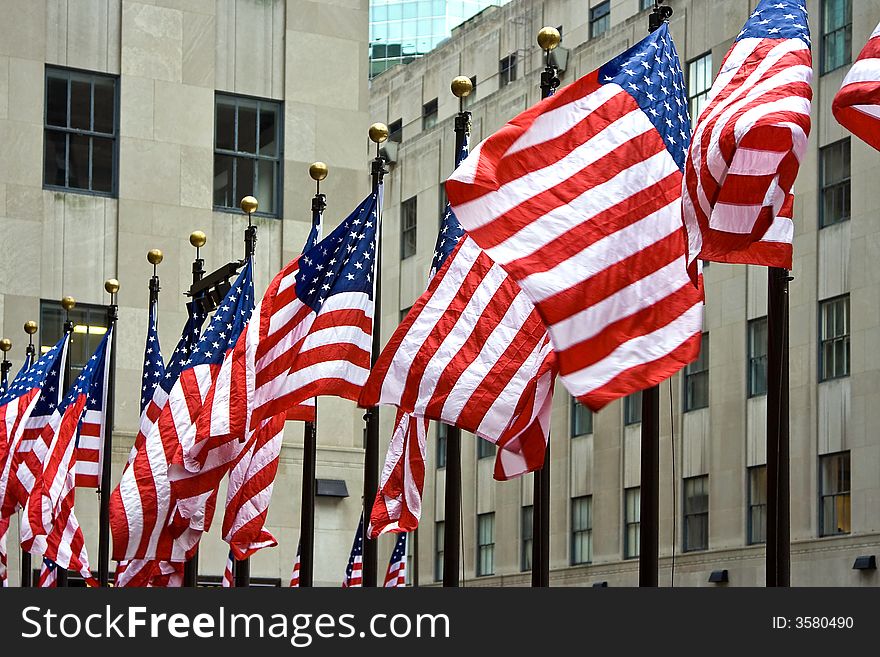 Wind is blowing through a row of American flags at the Rockefeller Center in New York City