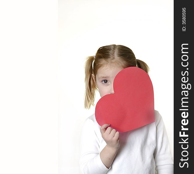 Little girl dressed in white holding a valentine heart. Little girl dressed in white holding a valentine heart