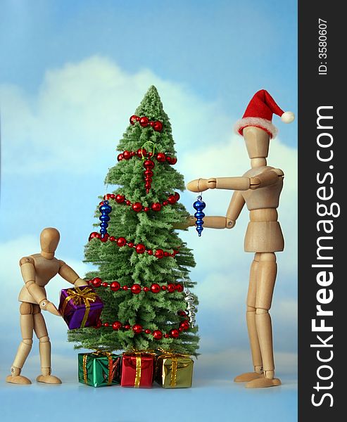 Adult and child wooden figures decorating a Christmas Tree. Adult and child wooden figures decorating a Christmas Tree.