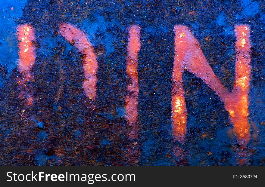 Image shows a metallic surface with the letters D, I, N been faded by rust and weathering. Image shows a metallic surface with the letters D, I, N been faded by rust and weathering