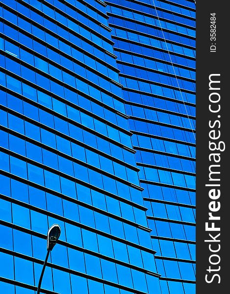 Close crop of a modern skyscraper with mirrored blue glass. Close crop of a modern skyscraper with mirrored blue glass.