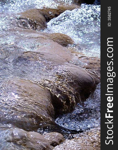 Bubbling water over rocks in sunlight. Bubbling water over rocks in sunlight