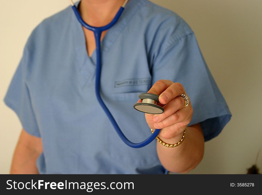 A doctor or nurse in scrubs reaching with the stethoscope