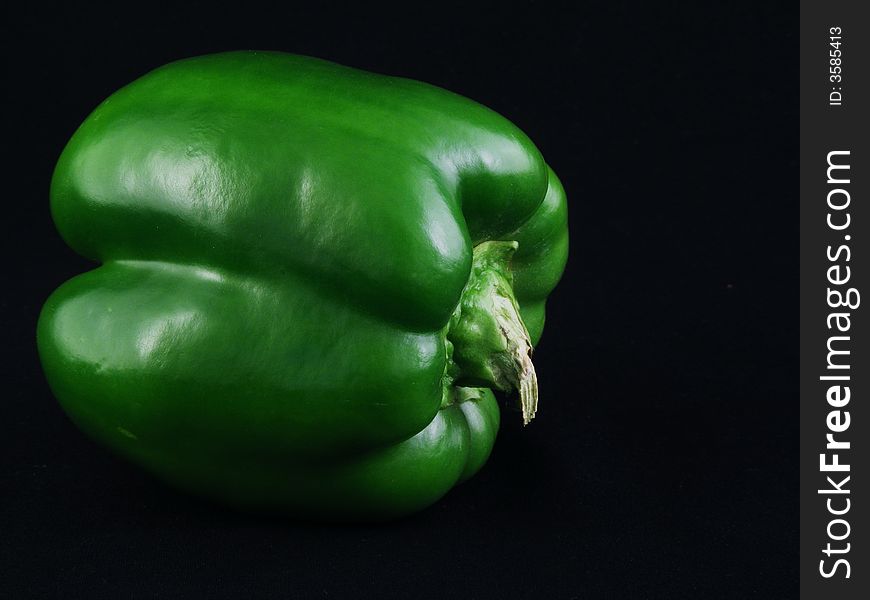 A green bell pepper against a black background.