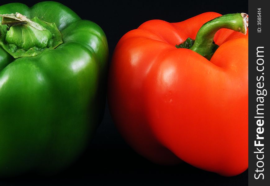 Red and green bell peppers against a black background.