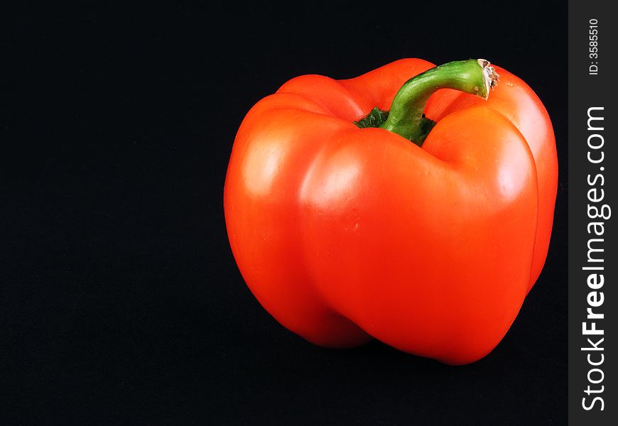 A red bell pepper against a black background.