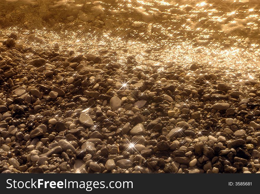 Beach Stones And Clear Water With Sun