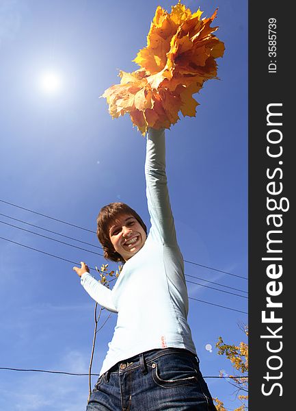 A girl in a chaplet from yellow maple leaves puts a person a sun