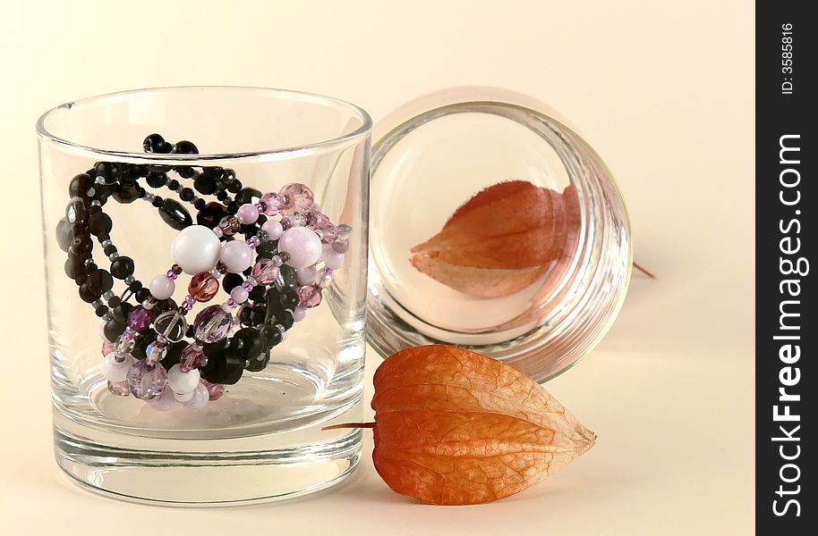 Still life with dry flowers, dry ground cherry (b.n. cape gooseberry), two bracelets and two glasses on sandy yellow background. Still life with dry flowers, dry ground cherry (b.n. cape gooseberry), two bracelets and two glasses on sandy yellow background