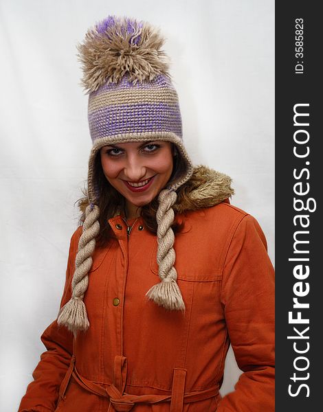 Winter portrait of beautiful young woman which freezes in an orange jacket