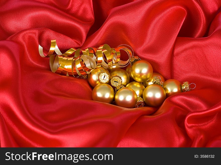Gold christmas balls on the red satin background. Gold christmas balls on the red satin background