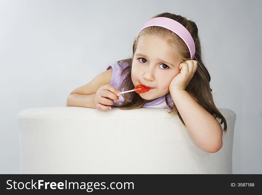 Nice young girl in pink on light background with lollipop