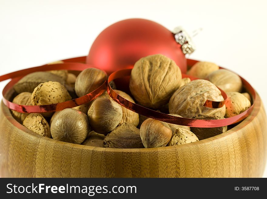 Wooden bowl with variety of nuts with red ornamental ball. Wooden bowl with variety of nuts with red ornamental ball