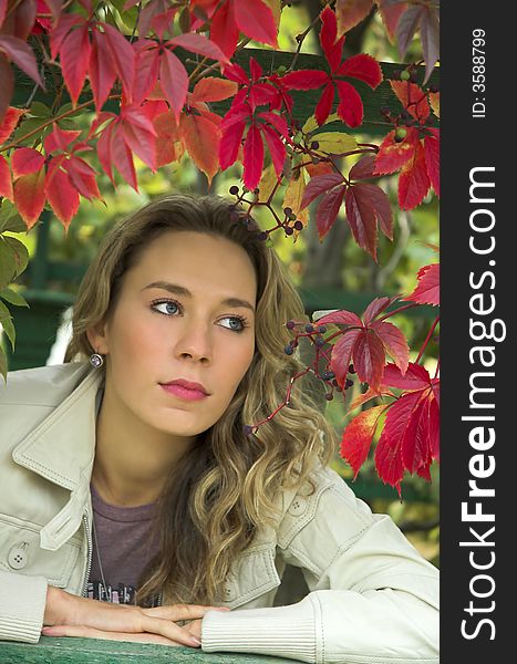 The beautiful blonde in red leaves of grapes