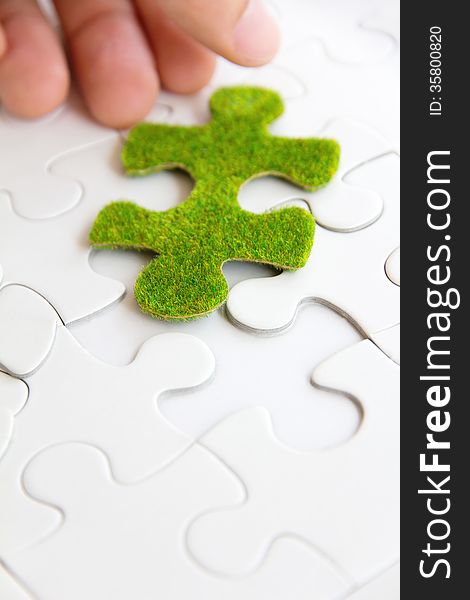 Hand holding a green puzzle piece