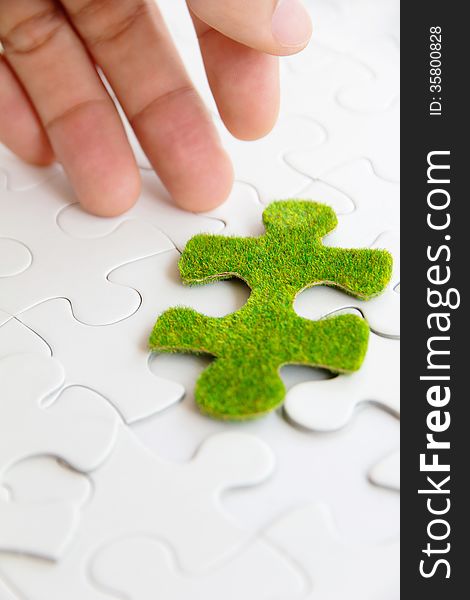 Hand holding a green puzzle piece, green space concept