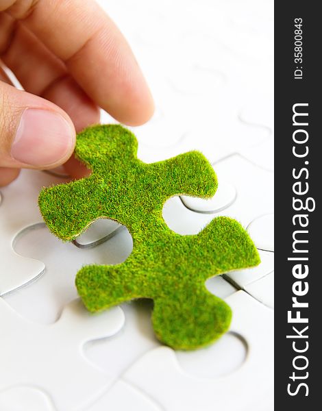 Hand holding a green puzzle piece, green space concept