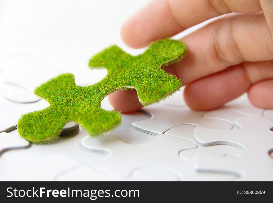 Hand holding a green puzzle piece, green space concept