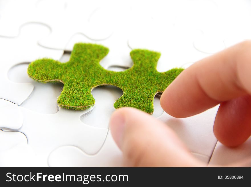Hand holding a green puzzle piece, green space concept