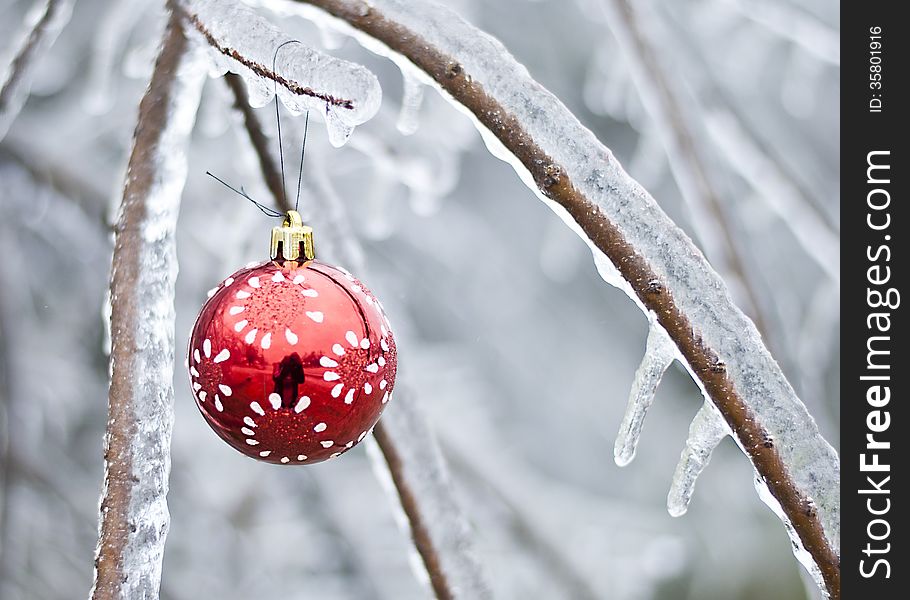 White on red Christmas ornament hanging from icy branch in winter scene. White on red Christmas ornament hanging from icy branch in winter scene.