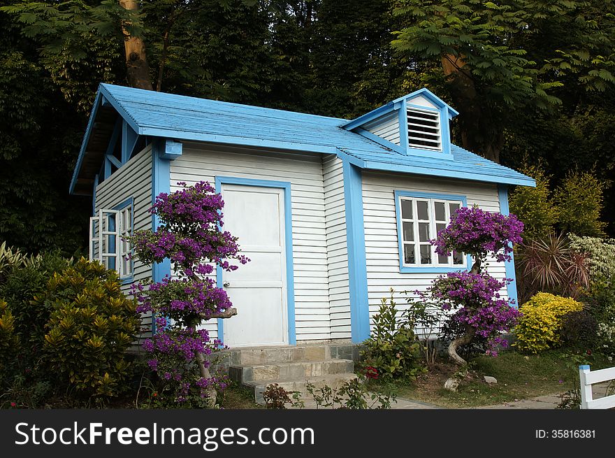 Wooden cabin among trees and flowers.