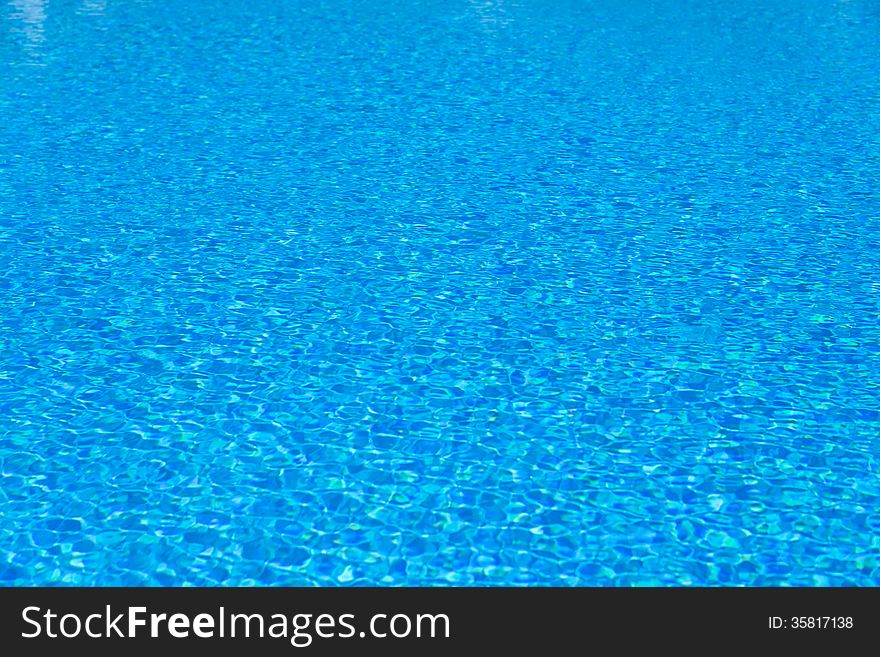 Background of blue water in the pool with the reflection of the sun