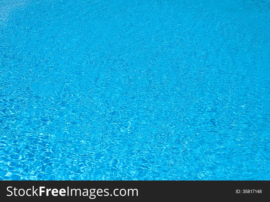 Background of blue water in the pool with the reflection of the sun