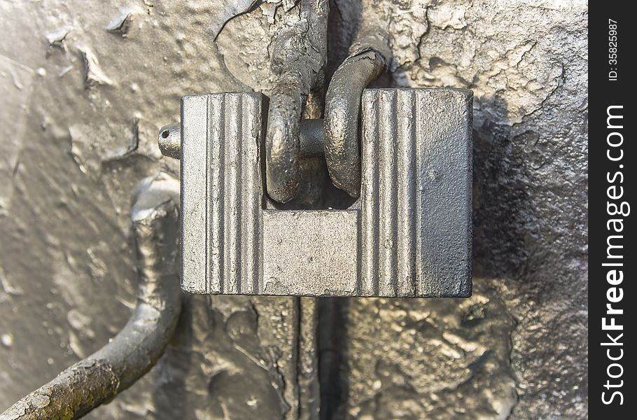 Old padlock on the metal gate in silver.