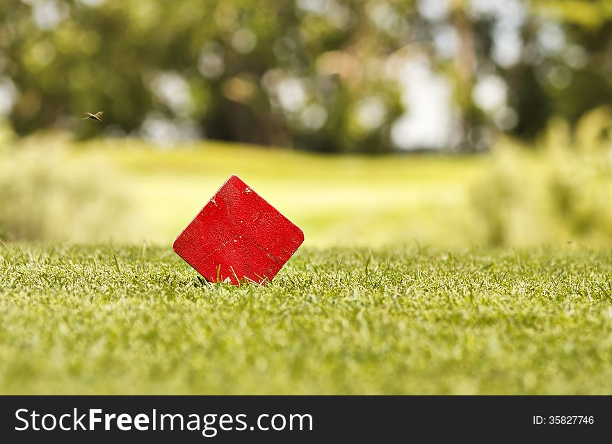 Red block of wood on a golf coarse