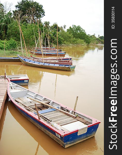 A scenery of boat at the lake with peaceful water and forest