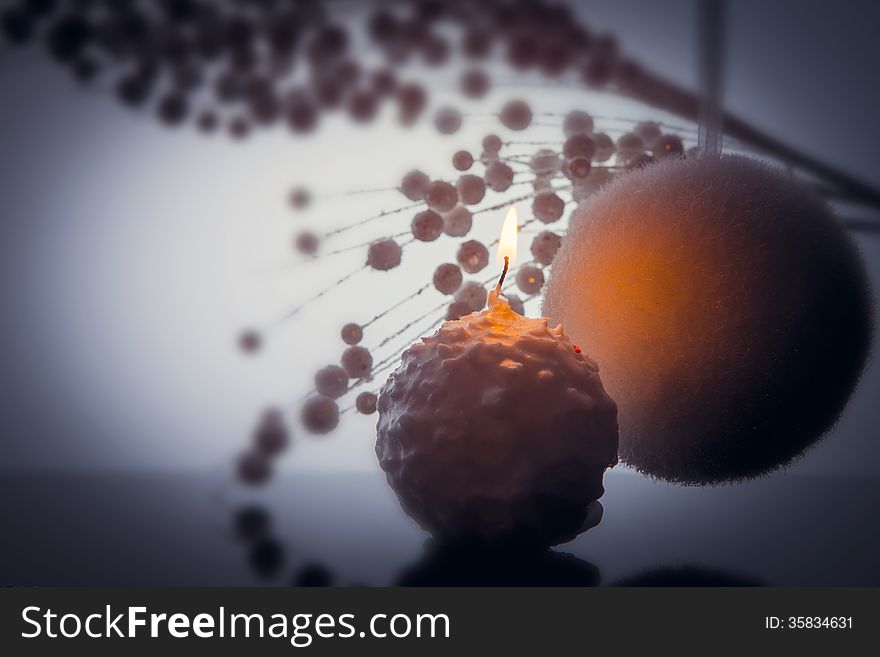 Merry Christmas decoration in white color. Burning candle, big soft bubble and thin twigs with small snow bubbles. Over reflecting surface and grey color background. Merry Christmas decoration in white color. Burning candle, big soft bubble and thin twigs with small snow bubbles. Over reflecting surface and grey color background.