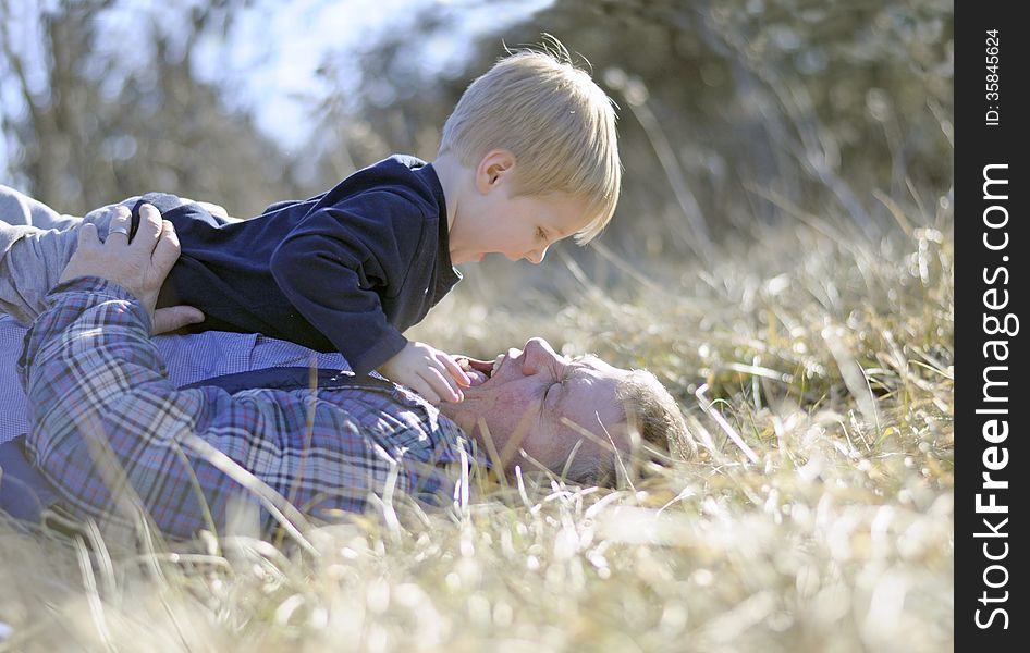 A men and his boy laying in the tall grass wrestling. A men and his boy laying in the tall grass wrestling.