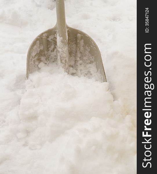 An isolated gray snow shovel removes fresh snow after a winter storm.