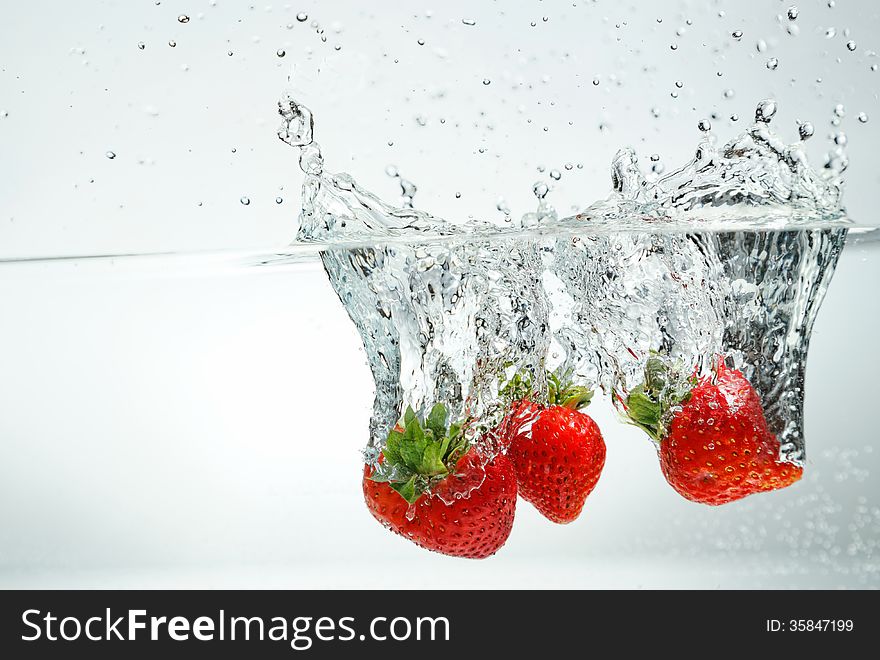 Fresh strawberry falling into the water making splash. Fresh strawberry falling into the water making splash