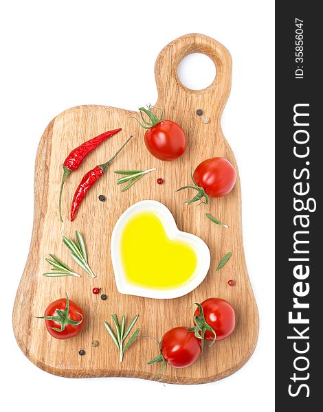 Cherry tomatoes, chili peppers, olive oil and spices on a wooden board isolated on white