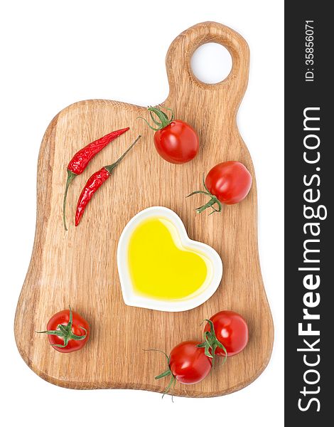 Cherry tomatoes, chilli and olive oil on wooden board, isolated